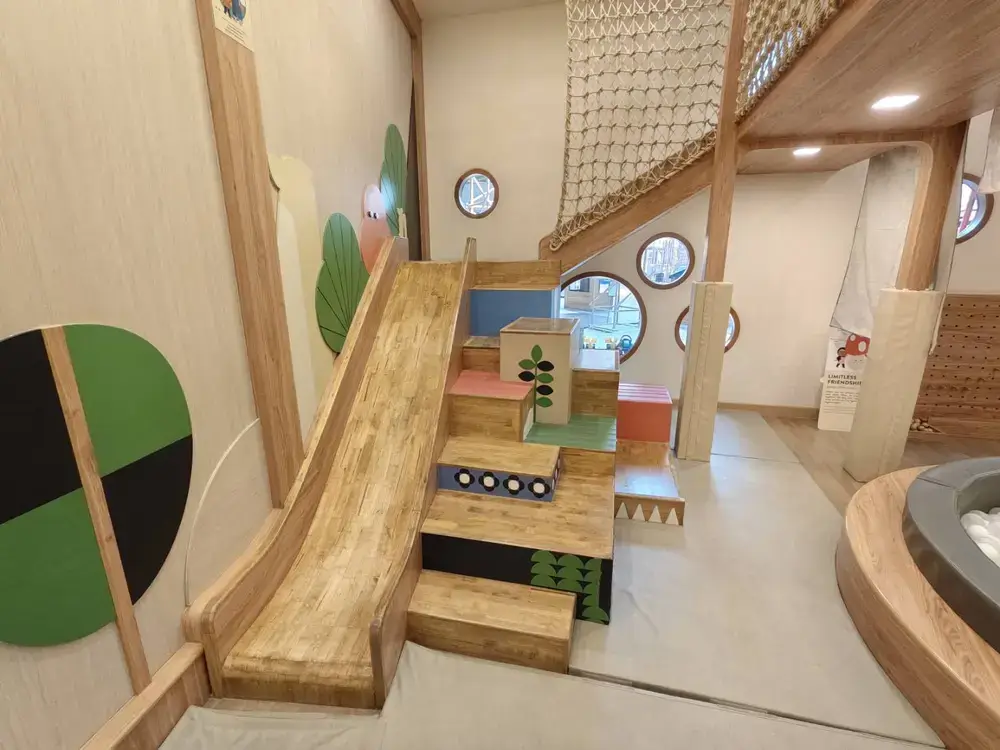 屋内にある大きな木製滑り台とアスレチック遊具。