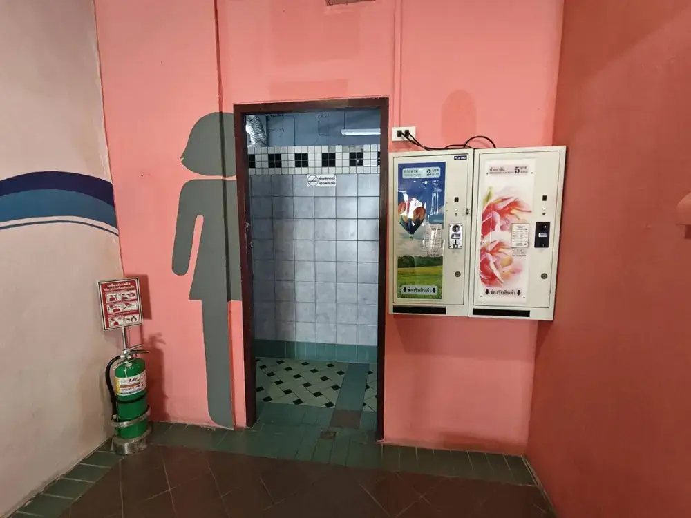 女性用トイレ・更衣室の入り口。ピンク色の壁にピクトグラム。