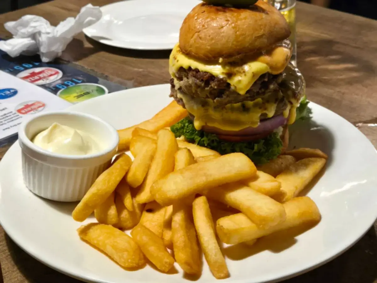 チーズを重ねたハンバーガーとフライドポテト、白いディップ